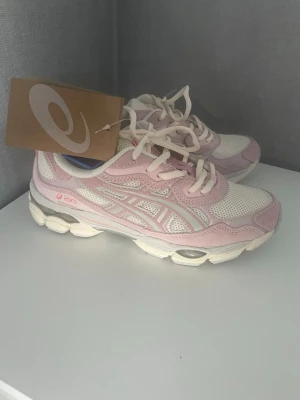 Asics Löparskor - Snygga sneakers från Asics i vitt och ljusrosa med mesh- och mockadetaljer. Skorna har en chunky sula och klassisk snörning. Perfekta för dig som gillar sportig stil och vill ha bekväma skor till vardags.