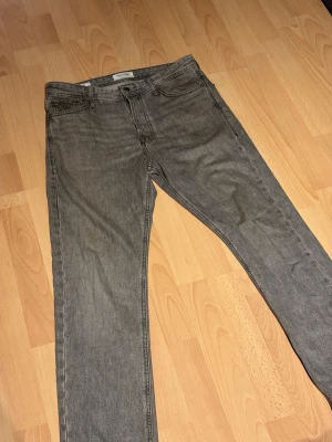Grå loose fit jeans - Säljer ett par gråa loose fit jeans med rak passform och klassisk femficksdesign. Jeansen har en enkel look och är perfekta för dig som gillar en avslappnad stil. Modellen heter LOOSE / CHRIS och materialet är denim. 28W/30L