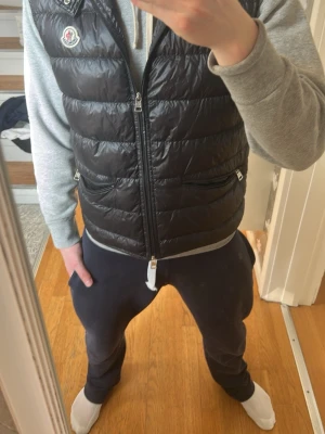 Svart Moncler gui väst - Säljer min svarta moncler gui väst! Västen är knappt använd och har storleken S, modellen på bilden är ungefär 171. Västen är köpt begnat hos sicuro fashion, inget kvitto tyvärr. Bara att höra av sig vid potentiella frågor!