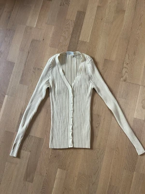 Tröja / kofta Weekday S - En ribbad kofta med knappar från Weekday. Storlek S. Färg: Offwhite Material: 70% viskos, 30% polyester