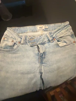Ljusblå mom jeans från 157 - Säljer ett par ljusblå mom jeans från 157 med klassisk femficksmodell och hög midja. Jeansen har bälteshällor och dragkedja framtill. Perfekta för en avslappnad och trendig look.