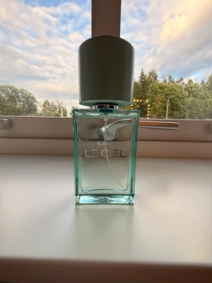 CAIA Le Ciel parfym - Fräsch parfym från CAIA med namnet Le Ciel. Flaskan är rektangulär i genomskinligt glas med ljusblått lock och minimalistisk design. Perfekt för dig som gillar stilrena och moderna doftflaskor.