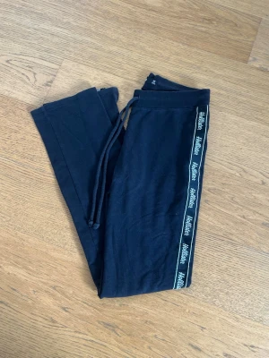 Svarta mjukisbyxor från Hollister XS - Svarta mjukisbyxor från Hollister med dragsko i midjan och ribbad linning. Snygg detalj med Hollister-logga längs sidorna. Sköna och mjuka, perfekta för chill eller träning.