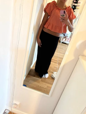 Korallfärgad croppad blus med volang - Säljer en söt korallfärgad blus med puffärmar och volangkant. Toppen är croppad och har en lös passform med resår vid halsringningen. Perfekt luftig topp till sommaren.