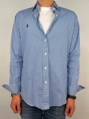 Ralph lauren skjorta M vit/blå randig - Säljer denna otroligt snygga ralph lauren skjorta. Riktigt skönt material . Size 15 1/2 som motsvarar M. Modellen är 180cm. Bredd 46cm,  längd 71cm! Fint skick, nytvättad och ny strykt så att skillnaden på denna och en ny ska vara minimal! Fraktar samma dag som köp, kan gå ner i pris vid snabb affär! 🤩