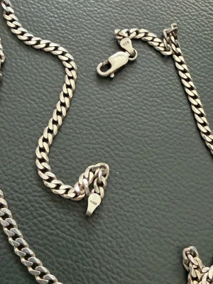 Kedjehalsband i silver 925 - Snyggt halsband i äkta silver 925 med klassisk pansarkedja. Halsbandet har en karbinhake och blanka, platta länkar som ger en stilren look. Perfekt accessoar för dig som gillar tidlös och enkel design.
