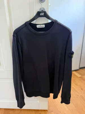 Svart sweatshirt från Stone Island - Mörkblå sweatshirt från Stone Island med klassisk rund hals och ikonisk patch. Perfekt för en clean och stilren look. Storlek S