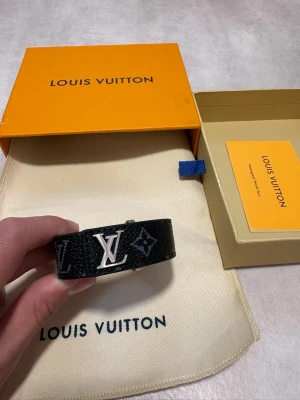 Louis Vuitton Monogram Eclipse Armband – LV - Louis Vuitton armband i svart Monogram Eclipse med LV-logga curb chain/länk. Mycket fint skick och sparsamt använt. Dustbag medföljer inte. Inga tydliga brister. Öppen för seriösa bud och frågor!