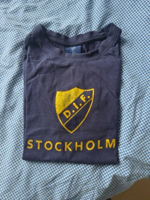 Blå DIF t-shirt - Schysst djurgårdstisha. Trycket har lossnat lite men man ser fortfarande texten DIF Stockholm tydligt. Köpt från difbutiken för ettt tag sedan. Säljer nu för endast 50 kr