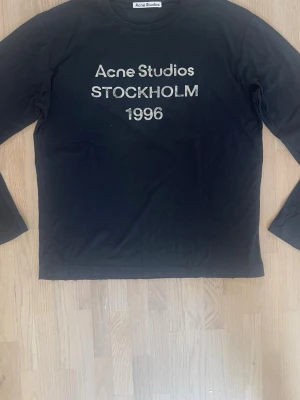 Acne Studios långärmad T-shirt – Svart, Oversized, Size S - Säljer denna Acne Studios långärmade T-shirt i svart. Storlek S med oversized passform som ger en avslappnad och lite baggy look.  Framtill finns trycket “Acne Studios Stockholm 1996” med en sliten/vintage finish som är en del av designen.  Säljer den eftersom den inte kommer till användning längre och mest ligger i garderoben.  Storlek: S Färg: Svart Passform: Oversized 🖤