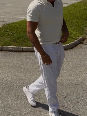Vit kortärmad piké  - Snygg vit t-shirt med korta ärmar och klassisk krage. Perfekt för en clean och fräsch look. Passformen är normal och materialet ser ut att vara mjuk bomull. Enkel att matcha med både jeans och linnebyxor. Inget märke men perfekt passform.