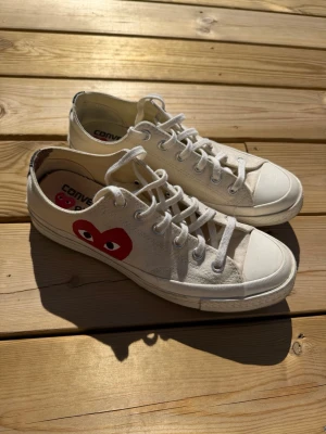  CDG Play Converse - Säljer ett par snygga vita Converse x Comme des Garçons Play skor. Skorna är i bra skick förutom en liten fläck på hälkappan på ena skon men inget som känns eller märks under användning :) skorna är storlek 41,5 och sitter väldigt true to size men jag hade dom också när jag hade storlek 42 så passar lite större och mindre! (Innermåt 26,5cm)