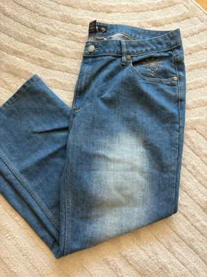 YLD Streetwear Jeans –  broderier fram & bak (Nyskick) - ett par riktigt schyssta ljusblå denimjeans från märket YLD (Your Local Dealer). Modellen är fylld med snygga detaljer: det klassiska Frihetsgudinnan-broderiet över hela bakfickan samt ett matchande broderi på framsidan vid fickan. De har en perfekt vintage/Y2K-look &  är använda max 1 gång och är därför i absolut nyskick.  * Storlek: W40/L32 