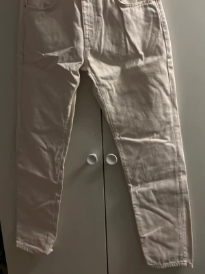Beiga raka jeans med hög midja - Säljer ett par beiga jeans med rak passform och hög midja. Jeansen har klassiska fem fickor och är sydda i ett kraftigare bomullstyg. Perfekta för dig som gillar en clean och enkel stil.
