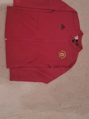Manchester United kofta - Hej! Jag säljer en Manchester United kofta i storlek S. Den är i mycket bra skick och har två fickor fram. Manchester United står skrivet på ryggen. Den är original och köpt från Manchester United shopen för 849 kr, men jag säljer den för 200 kr. Perfekt för alla United-fans! Hör av dig om du är intresserad!