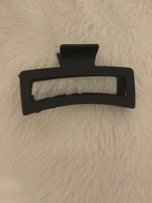 Svart rektangulär hårklämma - Stilren svart hårklämma i matt plast med rektangulär form. Längden på hårklämman är 13cm. Helt oanvänd, passade inte för mitt hår.