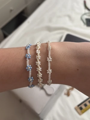 Blommiga pärlarmband  - Säljer tre handgjorda armband med små pärlor. Två armband är vitt med små blommor i pärlor, det andra är vitt med blå blommor. Och även ett vitt pärlarmband som är väldigt stilrent, på alla smycken kan man välja hur stort det ska vara. Köpte på en sida på instagram💕