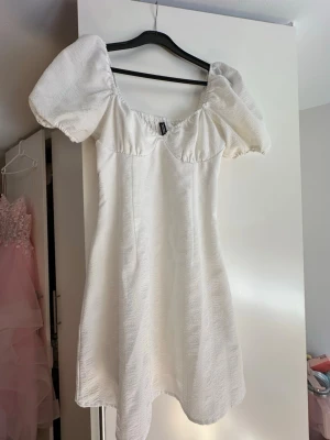 Vit kortklänning - Vit kort klänning med puffärmar och lätt struktur i tyget från H&M Divided. Använd 1 gång. 