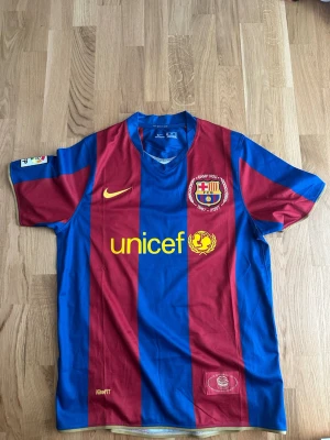 Barcelona matchtröja Abidal 22 - Säljer en klassisk FC Barcelona matchtröja med rödblåa vertikala ränder, gul Nike-logga och Unicef-tryck på bröstet. På ryggen står det Abidal och nummer 22 i gult. Tröjan har korta ärmar och klubbmärke på bröstet.