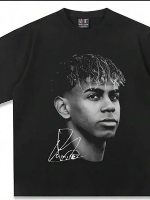 Svart t-shirt med porträtttryck - Cool svart t-shirt med stort porträtttryck av en ung man på framsidan och en vit signatur under motivet. Klassisk rund hals och korta ärmar. Perfekt för dig som vill sticka ut med en unik och personlig stil.