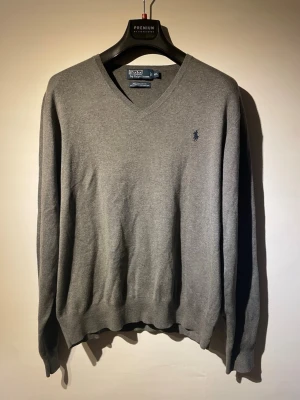 Polo Ralph lauren tröja, stickad  - Säljer en fin stickad tröja från Polo Ralph Lauren i färgen grå. Tröjan är i fint skick utan fläckar eller hål.                                                           Storlek: XXL, men sitter som en L/M i midjelängd.                                                                    Självklart äkta✅skickas oftast inom 24h efter köp. Hör av er vid funderingar!