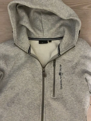 Ljusgrå hoodie från Sail Racing -  supersnygg hoodie från Sail racing den i 150 och Den är använd två gånger och skriv privat om mer information