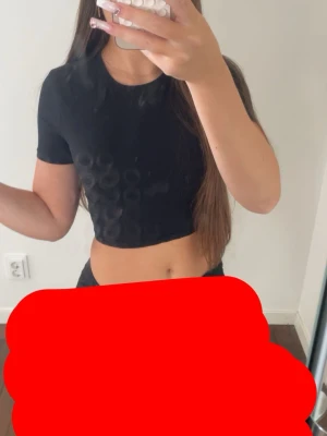 Svart croppad t-shirt - Snygg svart croppad t-shirt med rund halsringning och korta ärmar. Enkel och stilren design som passar perfekt till jeans eller kjol. Materialet ser ut att vara mjukt och stretchigt för en bekväm passform.