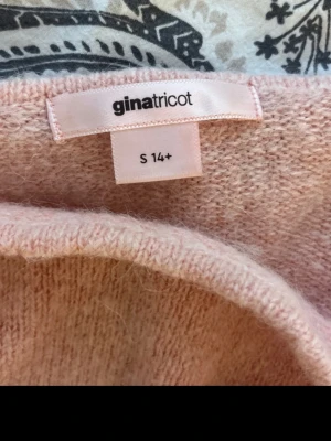 Ljusrosa stickad tröja Gina Tricot - Supersöt ljusrosa stickad tröja från Gina Tricot i storlek S. Tröjan har långa ärmar, bred ribbstickad nederkant och är gjord i ett mjukt, fluffigt material. Perfekt för att hålla sig varm och snygg under kyliga dagar.