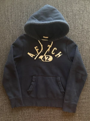 Abercrombie & fitch hoodie ~ sällsynt yk2  - Sjukt eftertraktad Abercrombie & Fitch hoodie ~ sällsynt vintage modell | st M | färg marinblå | snyggt sliten design som ger en naturlig vintagekänsla och slitna detaljer | klassisk passform | sällsynt 2000’s modell | OBS kan gå ner lite i pris vid snabb affär! 🏄