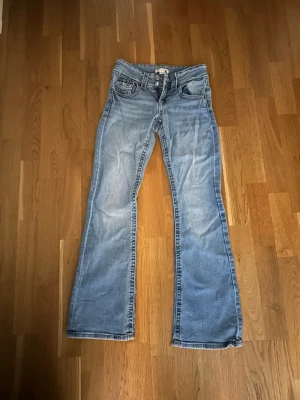 Ljusblå bootcut jeans - Säljer ett par ljusblå bootcut jeans med klassisk femficksdesign och låg midja från Gina tricot i storlek 152😊💕