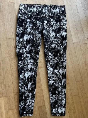 Svarta och vita träningsleggings Cubus storlek L  - Säljer ett par snygga träningsleggings från Cubus med svartvitt abstrakt mönster. De har hög midja och är tillverkade i ett stretchigt material som passar perfekt för gymmet eller löprundan. Tight passform och bekväma sömmar.