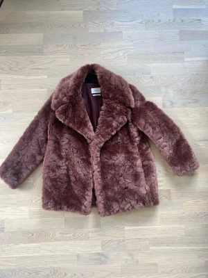 Filippa K Mörkrosa fuskpälsjacka - Säljer en fluffig mörkrosa fuskpälsjacka med bred krage och helknäppning. Jackan har en lyxig känsla och är helfodrad på insidan. Perfekt för dig som vill ha en trendig och varm look under vintern. Ny pris 4000kr