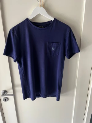 T-shirt från Polo Ralph Lauren - Limited edition design med loggan bröstficka!                                              Storlek: Small.                                     Snygg lila/marinblå t-shirt från Polo Ralph Lauren. Schysst cool lila färg. Passformen är klassisk/slim. Hör av er vid frågor eller behov av fler bilder! Mvh Axel