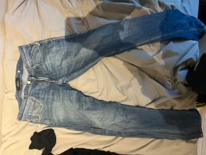 Blå replay jeans  - Säljer ett par klassiska blå jeans med raka ben och lätt slitna detaljer. Jeansen har fem fickor, knappgylf och kontrastsömmar. Perfekta till en avslappnad stil. Sitter mycket skönt skriv vid frågor!!