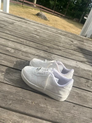 Vita klassiska sneakers i läder - Snygga helvita sneakers med lågt skaft och perforerade detaljer på tån. Skorna har en stilren design med vita skosnören och sula. Tillverkade i läder med diskreta sömmar och enkel logga på hälen. Perfekta för en clean och fräsch look.