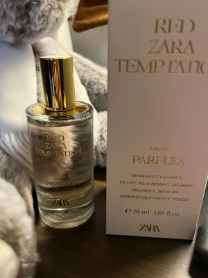 ZARA Red Temptation Eau de Parfum - Zara Red Temptation Eau de Parfum (50 ml). Doften beskrivs som varm, magnetisk och beroendeframkallande (Gourmand woody amber) med härliga noter av bitter apelsin, saffran, pralin och jasmin på en varm bas av bärnsten och trä. Parfymen är sparsamt använd endast ett fåtal gånger (se kvarvarande mängd på bilderna) och har förvarats mörkt och svalt. Originalkartong medföljer. 