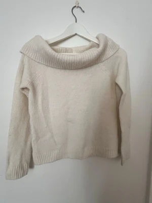 Vit/beige stickad tröja från Gina Tricot - Vit/beige stickad tröja från Gina Tricot med bred polokrage och långa ärmar. Tröjan har ribbstickade muddar vid ärmslut och nederkant.
