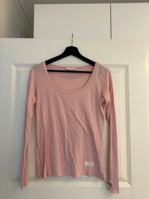 Ljusrosa långärmad topp Odd Molly - Ljusrosa långärmad topp från Odd Molly med rundad halsringning. Tillverkad i mjuk bomull. En liten etikett med logga sitter nertill på framsidan. Små hål fram, se bild 