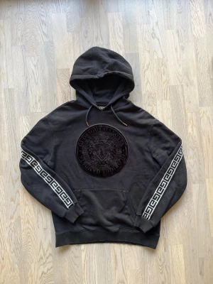 Glorious Gangsta hoodie - M, svart - Bra skick. Finns tecken på användning - hål, slitage (se bilder)  Hoodie från Glorious Gangsta, storlek M, svart Broderad logga och mönstrade ärmar, huva med snörning, stor framficka.  Använt skick med små hål/slitage vid båda armbågarna. Liten lagning vid ficka (se bild). Fortfarande fullt användbar  Bröstvidd: 57 cm Längd: 66 cm 79% bomull, 21% polyester