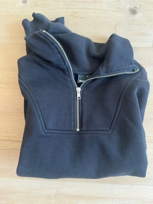 Svart collegetröja Gina Tricot - En svart collegetröja med snygg silvrig detalj framtill 