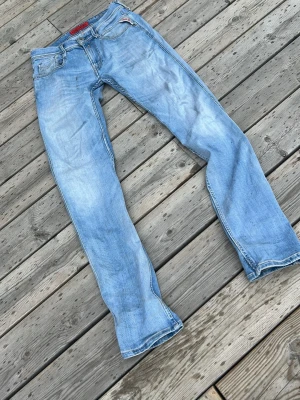 Ljusblå raka jeans från Diesel - Säljer ett par ljusblå jeans från Diesel med raka ben och klassisk femficksmodell. Jeansen har en röd Diesel-detalj vid myntfickan och bälteshällor. Materialet är denim i bomull och passformen är avslappnad men ändå snygg.