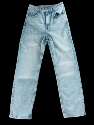 Never Denim W28 L32 herrjeans i vintage-stil - Säljer ett par ljusblå jeans med rak passform och hög midja. Jeansen har klassisk femficksdesign och är tillverkade i ett kraftigt denimtyg. Perfekta för dig som gillar retro och avslappnad stil. Finns i rök- och djurfritt hem. 