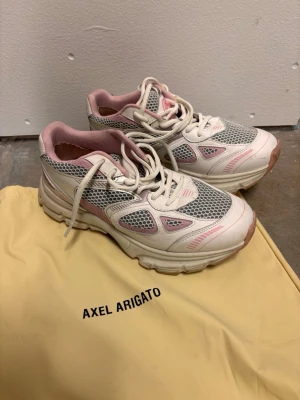 Axel Arigato Marathon Runner sneakers, strl 39 - Snygga sneakers från Axel Arigato i modellen Marathon Runner. Skorna är vita med rosa och grå detaljer, har meshpaneler för extra ventilation och en chunky sula. Använda 2 gånger