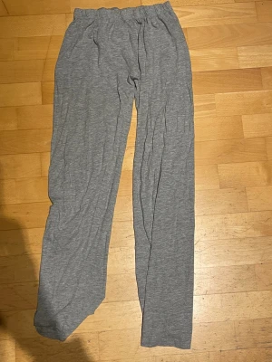 Grå mjuka loungebyxor - Ett par grå loungebyxor i mjukt och stretchigt material med resår i midjan. Byxorna har raka ben och är perfekta för att chilla hemma eller mysa runt i. Passar dig som gillar enkel och bekväm stil.