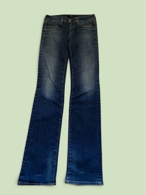 Blå bootcut Jeans 26/32 - Snygga blå bootcut jeans med lätt slitna detaljer och klassisk femficksmodell. Jeansen har en något utsvängd passform nedtill och subtila tvättade partier framtill och baktill. Perfekta för en avslappnad och trendig look.