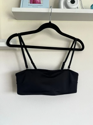 Svart bandeau bikinitopp - En bandeau-bikinitopp med avtagbara axelband. Storlek M. Aldrig använd.