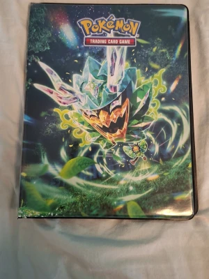 Pokémon samlarpärm med GX-kort - Säljer en Pokémon Trading Card Game samlarpärm med färgglatt motiv på framsidan. Inuti finns flera sidor med holografiska GX-kort i plastfickor. Perfekt för dig som vill utöka din samling eller börja samla Pokémonkort.
