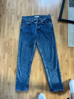 Blå raka jeans från ZARA - Säljer ett par klassiska blå jeans från ZARA med rak passform och hög midja. Jeansen har knappgylf, fem fickor och är gjorda i kraftigt denimtyg. Perfekta till en avslappnad och trendig look.