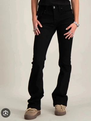 Svarta True Religion Jeans  - Snygga svarta bootcut jeans med klassisk femficksdesign och knappgylf. Jeansen har utsvängda ben och sitter tajt över låren för en modern siluett. Perfekta till sneakers eller boots och passar till många olika stilar. 🩷🫶🏼