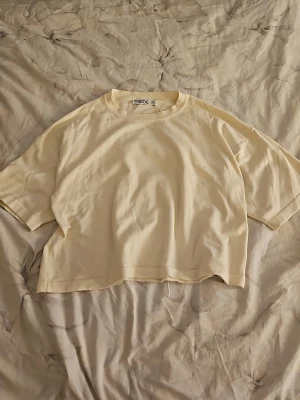 Beige croppad t-shirt från Inside - Säljer en beige croppad t-shirt från Inside. T-shirten har korta ärmar, rund halsringning och en loose passform. Perfekt för dig som gillar en enkel och clean stil. Tillverkad i mjuk bomull för maximal komfort.